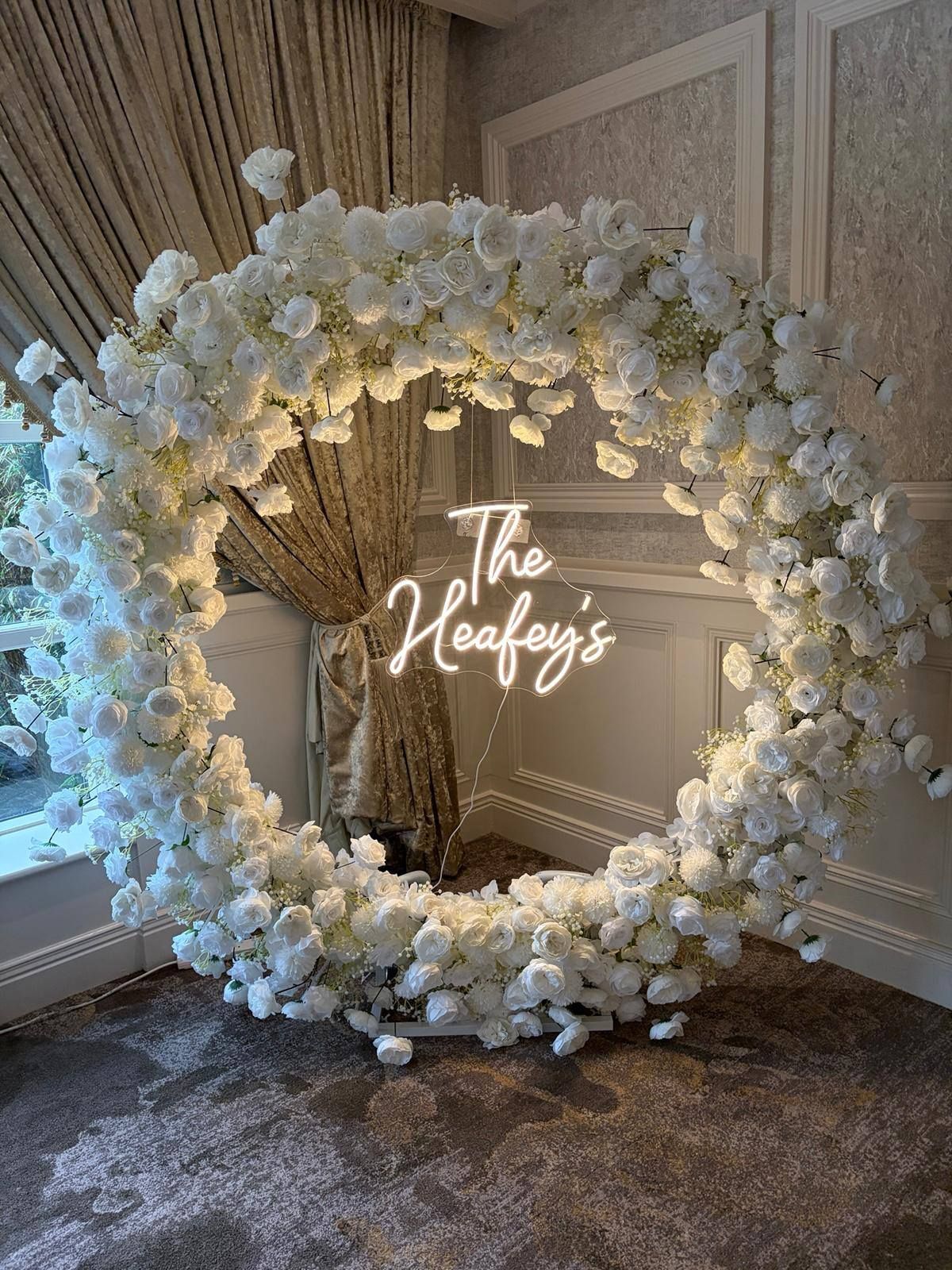 Large white flower wreath surrounding the newly weds family name. 